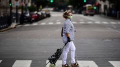 A woman wears a face mask and gloves against the spread of the new coronavirus as she crosses the empty Callao Avenue in Buenos Aires, on March 30, 2020. - Compulsory social isolation was extended until April 12 in Argentina, the government announced Sunday as 820 people infected and 20 dead were so far reported in the South American nation. (Photo by RONALDO SCHEMIDT / AFP)