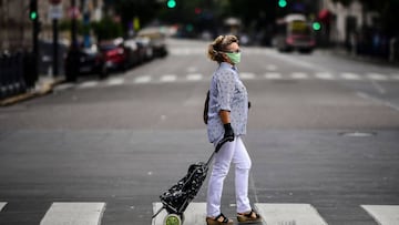 A woman wears a face mask and gloves against the spread of the new coronavirus as she crosses the empty Callao Avenue in Buenos Aires, on March 30, 2020. - Compulsory social isolation was extended until April 12 in Argentina, the government announced Sunday as 820 people infected and 20 dead were so far reported in the South American nation. (Photo by RONALDO SCHEMIDT / AFP)