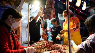 Workers wearing facemasks make a barbecue at a market in Wuhan in China&#039;s central Hubei province on April 4, 2020. - China came to a standstill on Saturday to mourn patients and medical staff killed by the coronavirus, as the world&#039;s most populo