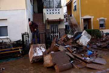 Un hombre observa los restos de las pertenencias de la gente tras las inundaciones en Utiel, España.