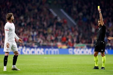 El árbitro Gil Manzano muestra la cartulina amarilla al defensa del Sevilla.