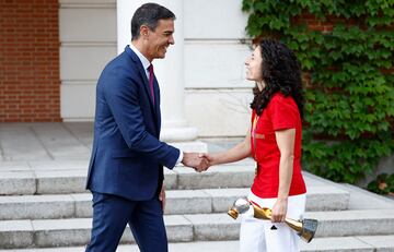 El presidente del Gobierno en funciones saluda a la capitana que sostiene el trofeo del mundial de fútbol femenino.