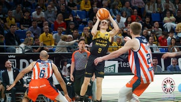 El base del Laguna Tenerife, Marcelinho Huertas (c), lanza a canasta ante los jugadores del Leyma Coruña, Phil Scrubbd (i) y Karlis Silins (d).