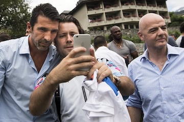 El portero italiano Gianluigi Buffon  y el presidente de la FIFA, el suizo Gianni Infantino, posan junto a un seguidor antes del partido que enfrenta a las leyendas del fútbol internacional, en Brig (Suiza)