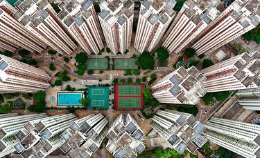 Esta espectacular imagen aérea muestra un complejo deportivo, con varias pistas de baloncesto, bádminton, tenis y una piscina, rodeado de rascacielos en la urbanización Richland Gardens, en la bahía de Kowloon, Hong Kong (China).  En una ciudad tan poblada hasta el espacio más pequeño es aprovechable para construir una instalación deportiva.