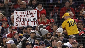 A fan holds up a sign mocking the Houston Astros sign-stealing cheating scandal during the first inning of game three of the MLB American League Championship Series between the Boston Red Sox and the Houston Astros at Fenway Park in Boston, Massachusetts,