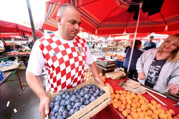 A salesman wearing Croatia's national colours carries fruit in a local market in Zagreb, on July  11, 2018, ahead of the 2018 Russia World Cup semi-final football match between Crotia and England. / AFP PHOTO / STR