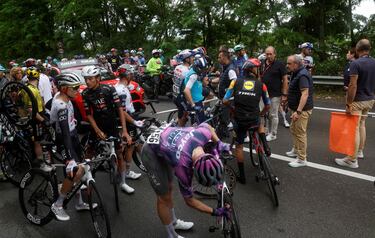 Los ciclistas conversan con los oficiales después de que la carrera se detuviera debido a varios accidentes durante la sexta etapa.