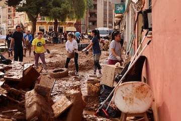 Voluntarios y vecinos ayudan a limpiar lugares afectados por las fuertes lluvias que provocaron inundaciones, en Paiporta.