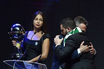 Brazil's Chapecoense Real club Plinio David (L) holds the Copa Sudamericana trophy beside Atletico Nacional de Medellin's representative Daniel Jimenez Ochoa, during the Libertadores Cup draw in Luque, Paraguay, on December 21, 2016