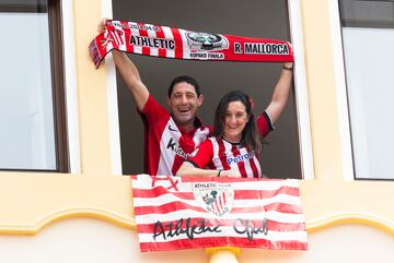 Una pareja de aficionados del Athletic muestran orgullosos sus colores desde un balcón.