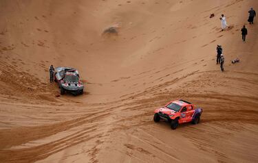 Un camarógrafo filma mientras el piloto español de Audi, Carlos Sainz espera mientras el copiloto Lucas Cruz inspecciona el automóvil después del accidente. 