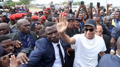 Paris Saint-Germain and France national football team star striker Kylian Mbappe (C-R) greets crowds gathered outside at the Yaounde Airport in Yaounde on July 6, 2023 as he arrives for a charity visit and a tour of his father's village. (Photo by Daniel BELOUMOU OLOMO / AFP)