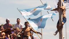 A fan of Argentina clinging to a pole cheers as the team parades on board a bus after winning the Qatar 2022 World Cup tournament, in Buenos Aires province, on December 20, 2022. - Millions of ecstatic fans are expected to cheer on their heroes as Argentina's World Cup winners led by captain Lionel Messi began their open-top bus parade of the capital Buenos Aires on Tuesday following their sensational victory over France. (Photo by TOMAS CUESTA / AFP)