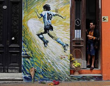 A man looks at flowers left next to a mural depicting Argentine football star Diego Maradona, in San Telmo neighborhood, Buenos Aires on November 25, 2020, on the day of his death. (Photo by ALEJANDRO PAGNI / AFP)