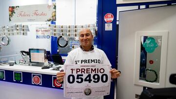 Un empleado de la administración situada en la calle Gran Vía posa con el número 5490 correspondiente al 'Gordo' del Sorteo Extraordinario de la Lotería de Navidad, a 22 de diciembre de 2022.