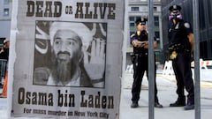 New York police stand near a wanted poster printed on a full page of a New York newspaper for Saudi-born militant Osama bin Laden, in the financial district of New York.