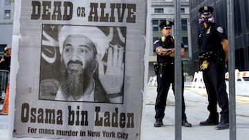 New York police stand near a wanted poster printed on a full page of a New York newspaper for Saudi-born militant Osama bin Laden, in the financial district of New York.