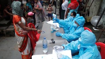 A healthcare worker checks the temperature of a resident during a medical campaign for the coronavirus disease at a slum area in Mumbai. 