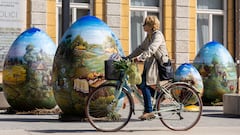 A woman drives on the bike next to sculptures depicting Easter eggs painted in the traditional naive art style in Koprivnica, Croatia, March 27, 2024. REUTERS/Antonio Bronic