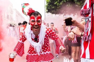 Aficionado rojiblanco vestido con traje de sevillana.
