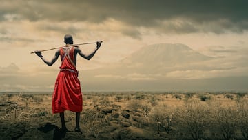 A masai man with traditional clothes watching Mount Kilimanjaro from the Amboseli National Park.