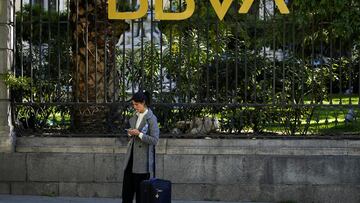 FILE PHOTO: A woman scans through her phone outside a BBVA bank building in Madrid, Spain, November 15, 2021. REUTERS/Juan Medina/File Photo