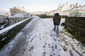 Un hombre camina sobre una ligera capa de nieve en la muralla romana de Lugo, Galicia (España). La cota de nieve está en 400 metros y ha sido acompañada por un descenso de las temperaturas. La situación más complicada está en las carreteras de la red secundaria de la montaña, donde muchas vías están cortadas al tráfico como consecuencia de árboles que se han desplomado por el peso de la nieve, pero también por las placas de hielo y la nieve en la carretera que dificultan la circulación.