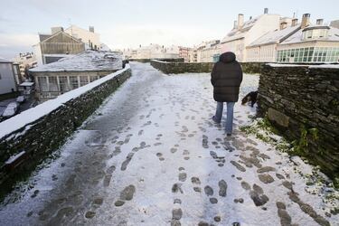 Un hombre camina sobre una ligera capa de nieve en la muralla romana de Lugo, Galicia (España). La cota de nieve está en 400 metros y ha sido acompañada por un descenso de las temperaturas. La situación más complicada está en las carreteras de la red secundaria de la montaña, donde muchas vías están cortadas al tráfico como consecuencia de árboles que se han desplomado por el peso de la nieve, pero también por las placas de hielo y la nieve en la carretera que dificultan la circulación.
