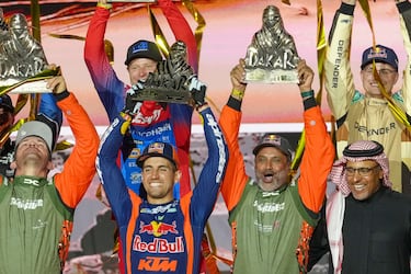 El piloto Luciano Benavides (centro izquierda) y el piloto Nasser Al-Attiyah (centro derecha) celebran en el podio alzando el trofeo del Rally Dakar. 