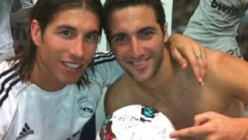 Higuaín y Ramos en el vestuario del Madrid con el balón firmado para el Pipita tras su hat-trick al Betis.