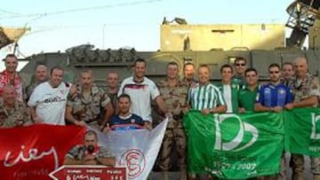 <b>RIVALIDAD.</b> Soldados de la Agrupación 21 de Sevilla en Afganistán posan con banderas de los equipos.