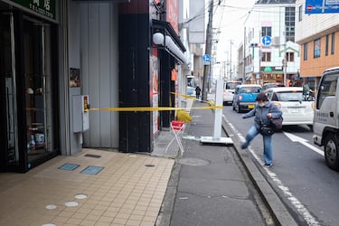 Una mujer pasa junto a un edificio con ventanas y paredes agrietadas, acordonado tras el terremoto.
