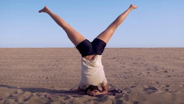 Maria Hidalgo realizando ejercicios para el snowboard en la playa. Con la cabeza apoyada en el suelo, las piernas levantadas y separadas.