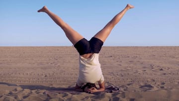 Maria Hidalgo realizando ejercicios para el snowboard en la playa. Con la cabeza apoyada en el suelo, las piernas levantadas y separadas. 