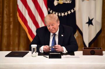 US President Donald Trump looks at a pre-paid debit card sat in the Cabinet Room of the White House in Washington, DC.