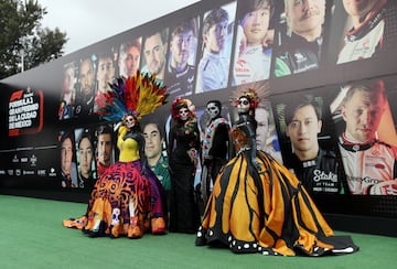 Aficionados vestidos con trajes de catrinas posan delante del  Autódromo Hermanos Rodríguez en el previo al GP de México.