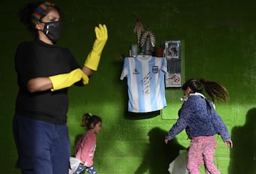 Unas niñas juegan delante de un pequeño altar en el que cuelga una réplica de la camiseta de Argentina de la
final del Mundial 86, firmada por Maradona. La imagen corresponde a un restaurante de Buenos Aires, que sorteará la elástica entre quienes donen alimentos para los más pobres durante esta crisis del coronavirus.