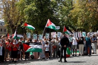 Agentes de la Guardia Civil observan a manifestantes pro-palestinos con banderas palestinas y carteles con la leyenda "Palestina Libre" durante la 20.ª etapa de la Vuelta a España 2025.