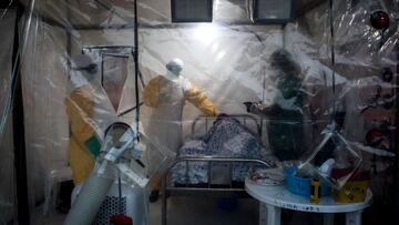 (FILES) In this file photo taken on August 15, 2018 Three medical workers check on an Ebola patient in a Biosecure Emergency care Unite (CUBE) on August 15, 2018 in Beni. - A woman died of the Ebola virus disease in eastern Democratic Republic of Congo on