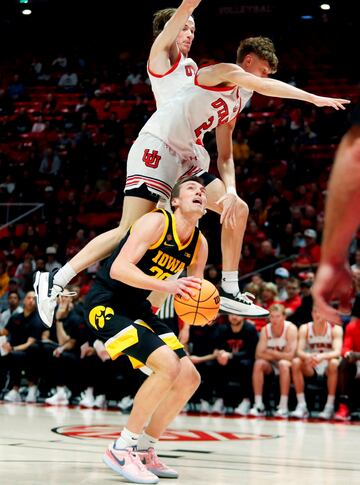 Brandon Carlson y Cole Bajema, de los Utah Utes, saltan por encima de Payton Sandfort, de los Iowa Hawkeyes, en un intento desesperado por taponarle durante un partido de segunda ronda del National Invitation Tournament.