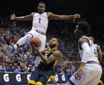 Jaysean Paige de los West Virginia Mountaineers corre hacia la canasta ante Wayne Selden Jr. y Devonte' Graham de los Kansas Jayhawks.