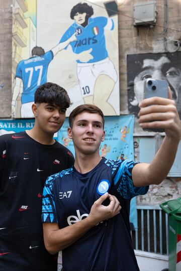 Dos hinchas del Nápoles se hacen un 'selfie' ante un cuadro de Kvaratskhelia y Maradona en los Quartiere Spagnoli de Nápoles.