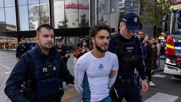 Police officers escort French urban climber Titouan Leduc (C) after he free climbed one of Europe's tallest skyscrapers, the Varso Tower in Warsaw, Poland, on September 27, 2025. Leduc, 24, was arrested by police while climbing the tower � barehanded and without protection, AFP journalists reported. The urban climber was arrested on the roof, 230 metres above the ground, before he could reach the 80-metre antenna above it. (Photo by Wojtek RADWANSKI / AFP)