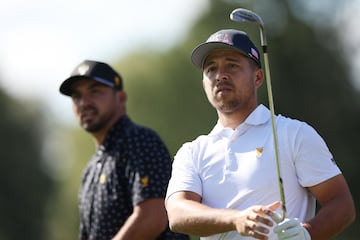 Xander Schauffele of the U.S. Team plays a shot on the eighth hole as Jason Day of Australia and the International Team looks on 