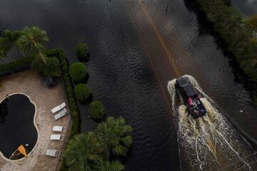 Varias personas viajan en la parte trasera de una camioneta para evitar las inundaciones en el vecindario de Tarpon Woods en Palm Harbor, Florida.