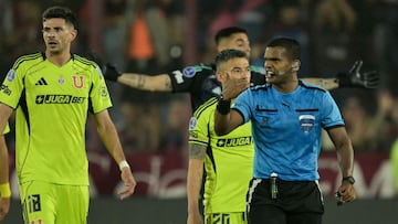 Venezuelan referee Alexis Herrera gestures past Universidad de Chile's Argentine forward #18 Lucas Di Yorio and midfielder #20 Charles Aranguiz during the Copa Sudamericana semifinal second leg football match between Argentina's Lanus and Chile's Universidad de Chile at the Ciudad de Lanus stadium in Lanus, Buenos Aires province, on October 30, 2025. (Photo by JUAN MABROMATA / AFP)