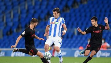 SAN SEBASTIAN, SPAIN - JULY 16: Mikel Oyarzabal (C) of Real Sociedad is challenged by Sergi Gomez (L) of Sevilla and Jesus Navas of Sevilla during the Liga match between Real Sociedad and Sevilla FC at Estadio Anoeta on July 16, 2020 in San Sebastian, Spa