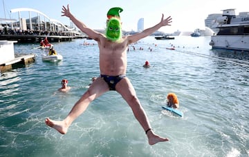 Un participante vestido con una máscara del Grinch salta al agua del puerto viejo de Barcelona, lugar donde empieza la tradicional Copa Nadal.