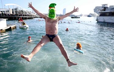 Un participante vestido con una máscara del Grinch salta al agua del puerto viejo de Barcelona, lugar donde empieza la tradicional Copa Nadal.